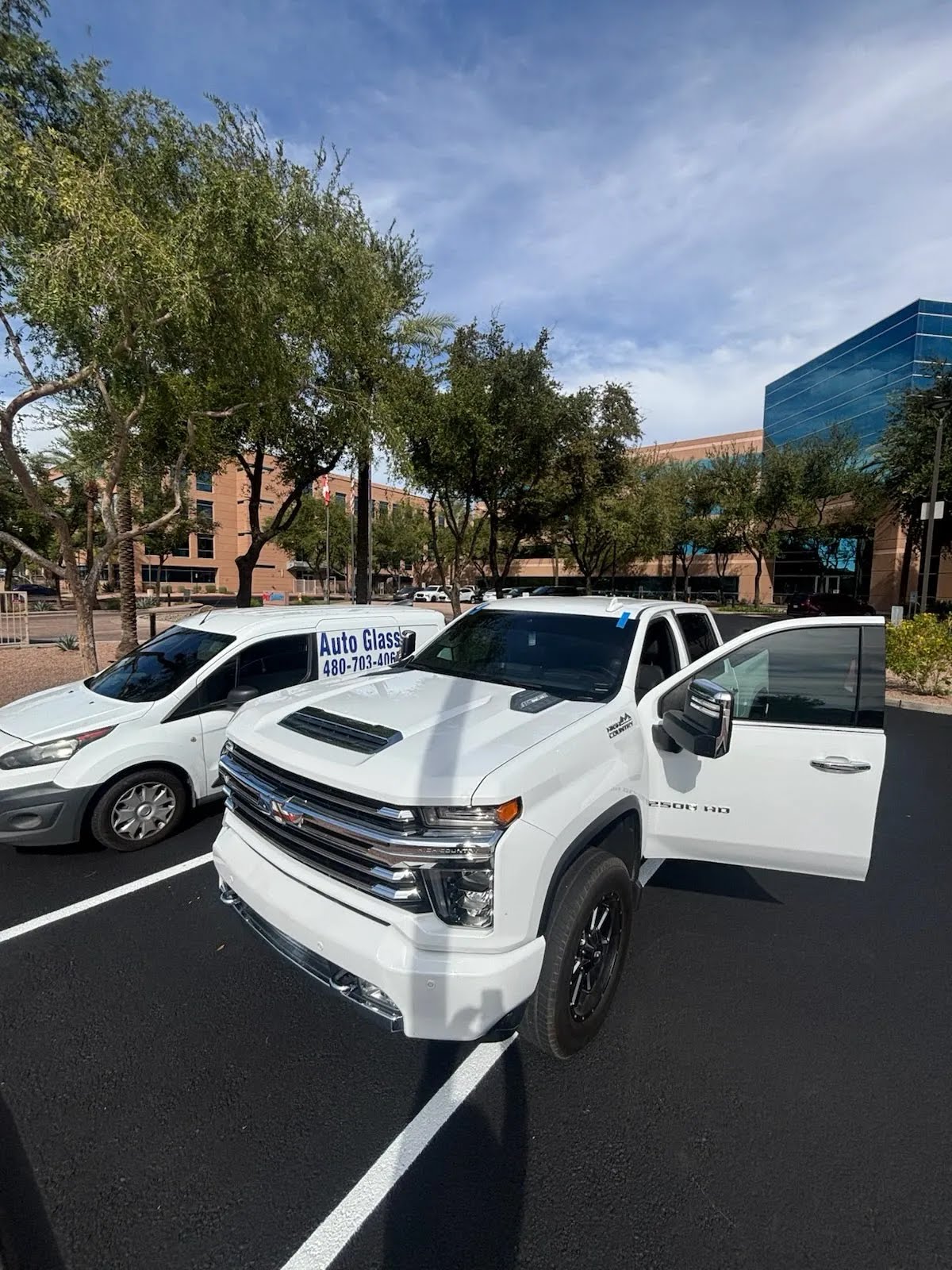 White Chevrolet Silverado HD beside the New Gen Auto Glass service van